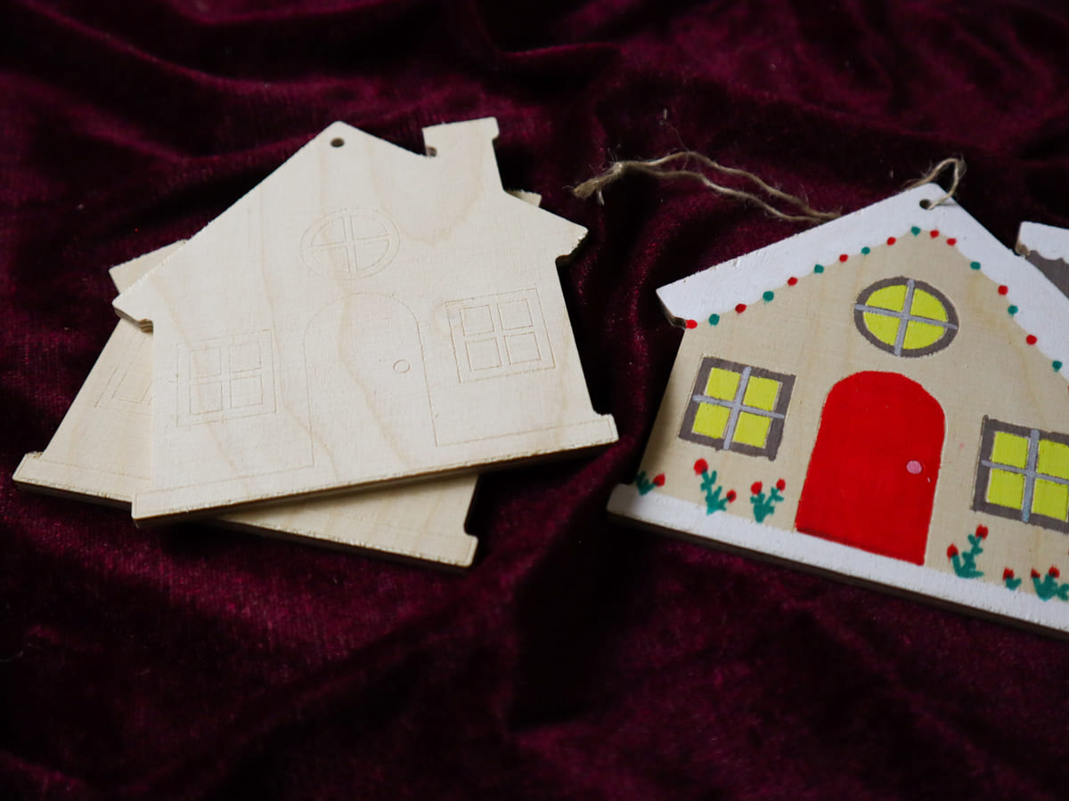 Maison de Noël en bois à suspendre de 11 × 11 cm, avec fenêtres et porte gravées.